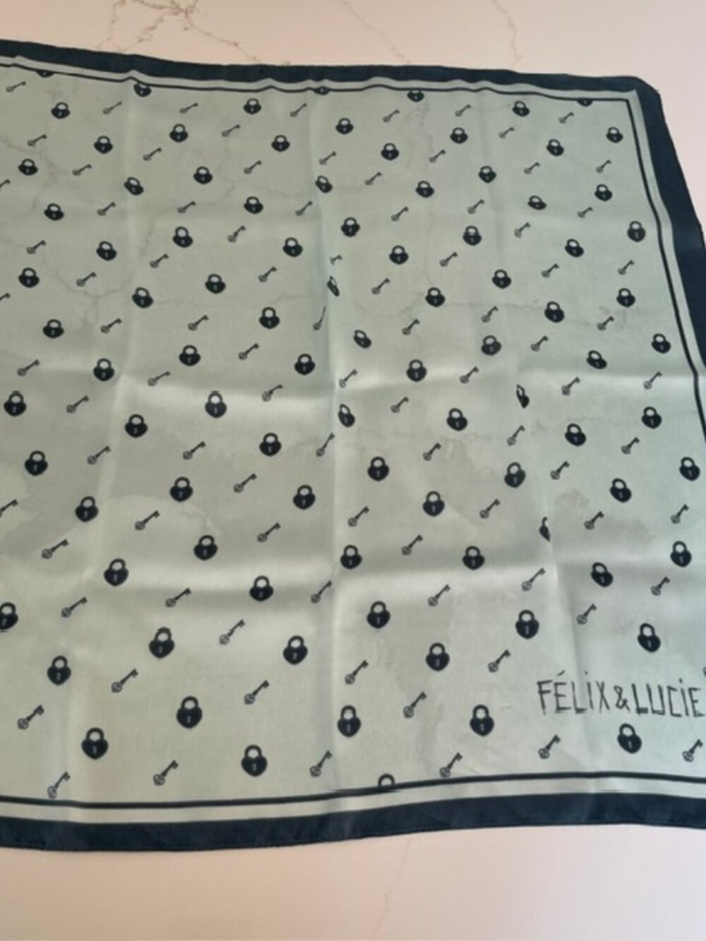 Padlock and key print square scarf from Felix & Lucie. Various tones of teal.